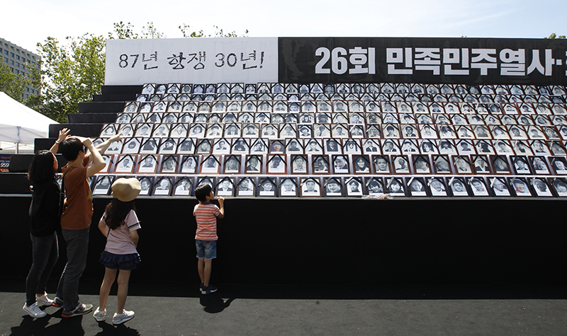 6·10 민주항쟁 30주년인 10일 오후 서울광장에서 열린 제26회 민족민주열사·희생자 범국민추모제에 마련된 영정들을 한 가족이 지켜보고 있다.