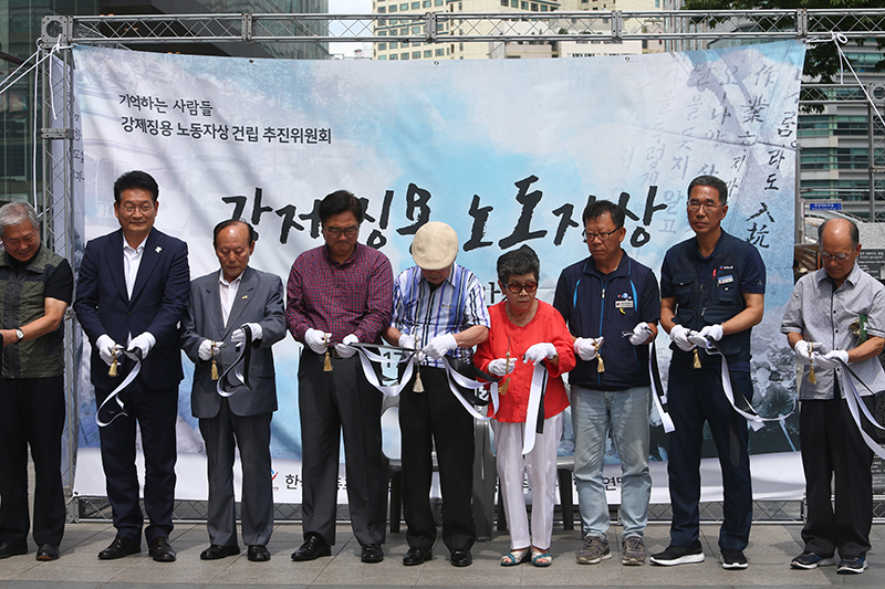 12일 오후 서울 용산역 광장에서 열린 '강제징용 노동자상 제막식'에서 강제징용 피해자인 김한수(99) 할아버지와 더불어민주당 우원식 원내대표, 송영길 의원 등이 용산역 광장에서 열린 강제징용 노동자상 제막식에서 커팅하고 있다.