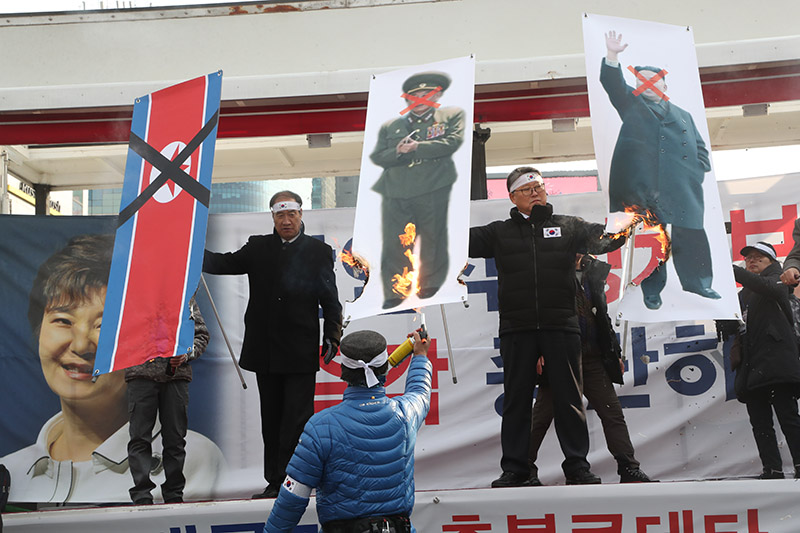 24일 오후 서울 용산구 서울역광장에서 대한애국당이 주최한 '김영철 방남하는 평양올림픽 반대' 집회에서 조원진 대한애국당 대표가 김정은 노동당 위원장과 김영철 노동당 중앙위원회 부위원장의 사진을 불태우고 있다.