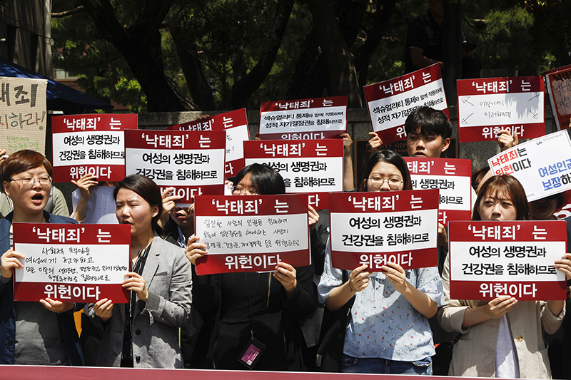 낙태법 폐지를 촉구하는 시민단체 회원들이 서울 종로구 헌법재판소 앞에서 낙태죄 폐지를 촉구하는 기자회견에서 위헌 손피켓을 들고 있다.