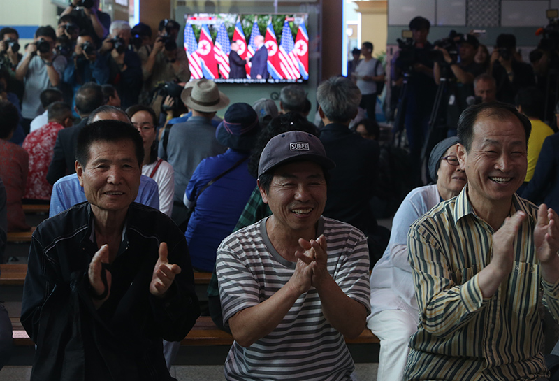 12일 서울역에서 시민들이 싱가포르에서 열린  도널드 트럼프 미국 대통령과 김정은 북한 국무위원장의 북미정상회담을 TV로 시청하며 박수를 치고 있다.