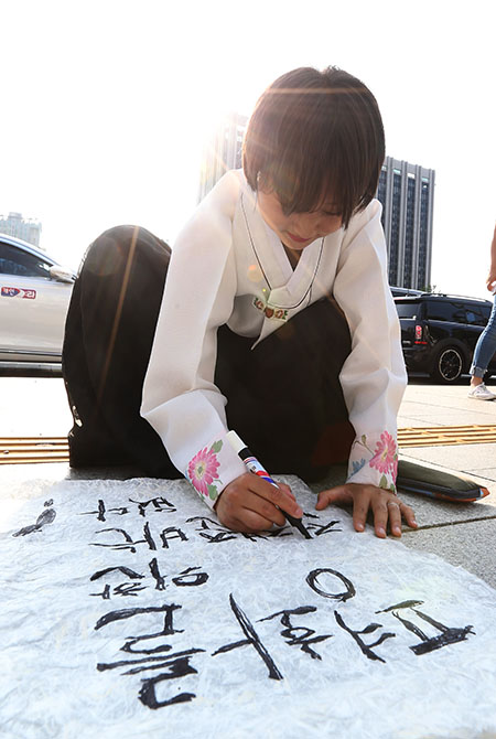 소녀상지킴이 대학생이 16일 오후 서울 종로구 대한민국역사박물관 앞에서 열린 '소녀상농성 900일 평화를 위한 전쟁준비 없다' 기자회견에서 평화를 염원하는 글을 쓰고 있다.