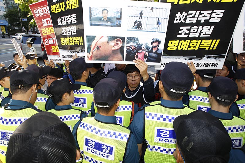 금속노조 쌍용자동차지부 조합원들이 12일 오전 서울 서대문구 경찰청 앞에서 지난 2009년 쌍용자동차 파업 강제 살인진압과 관련해 조현오 전 경찰청장의 처벌을 촉구하는 기자회견 중 피켓을 들고 조현오 전 청장이 탄 차량을 향해 피켓시위를 하고 있다.