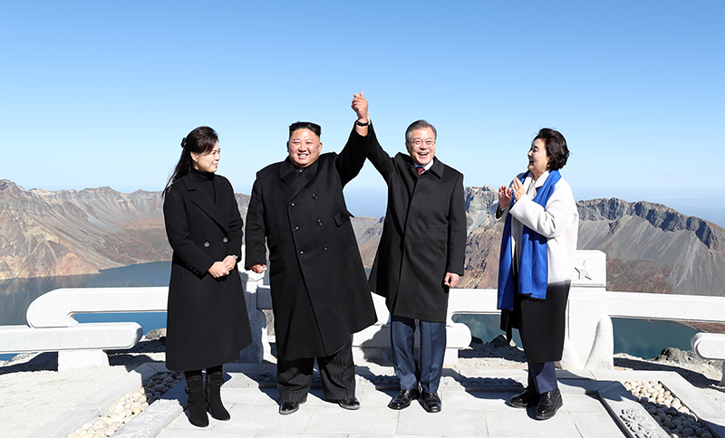 문재인 대통령과 김정은 국무위원장이 백두산 정상인 장군봉에 올라 손을 맞잡아 들어올리고 있다.