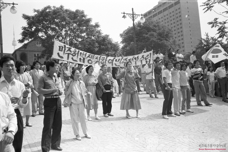 1987년 6월 명동성당에 모인 시민들이 '민주헌법 쟁취하여 민주정부수립' 현수막을 들고 구호를 외치고 있는 모습