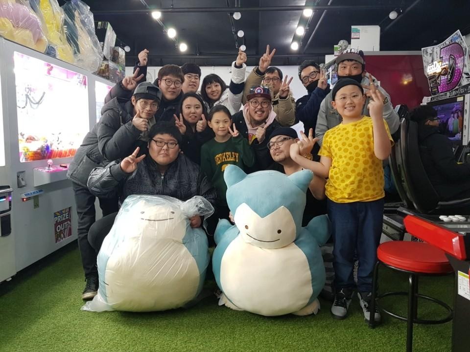 박광현씨가 자신이 운영하는 인형뽑기 가게에 찾아온 손님들과 함께 기념사진을 찍고 있다.