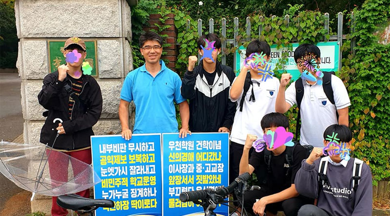 권종현 선생님이 낸 문제로 중간고사를 친 학생들이 하굣길에 1인 시위하는 선생님에게 ‘파이팅’을 외쳐주고 있다.<br