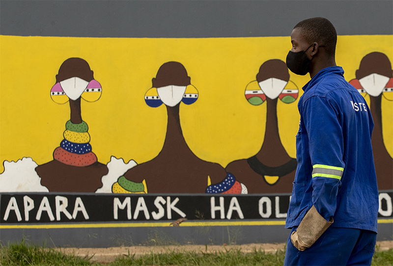 28일(현지시간) 남아프리카공화국 페레니힝의 세보켕에서 마스크를 쓴 한 남성이 공공장소에서의 마스크 사용을 홍보하는 벽화 앞을 지나고 있다.