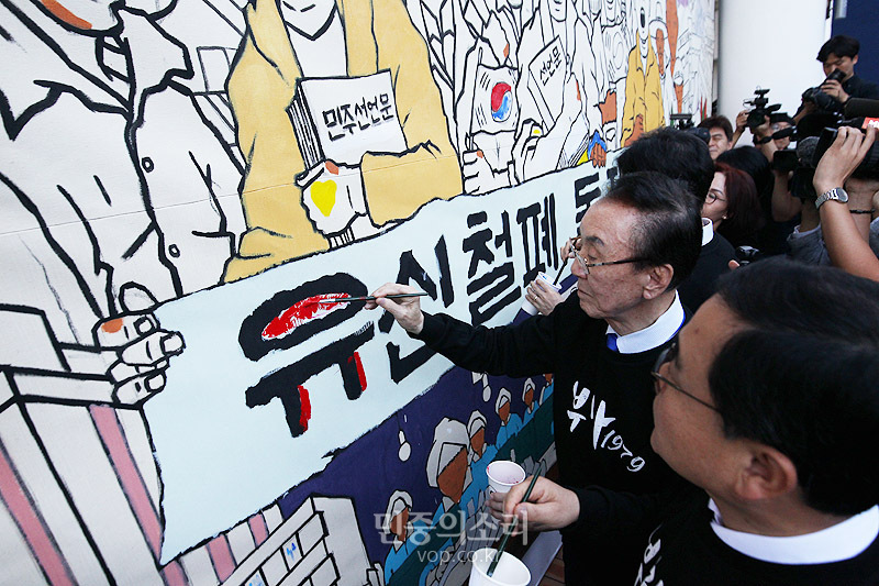 18일 부산대학교 10.16기념관에서 부마민주항쟁의 국가기념일 지정을 축하하는 부산시, 경남도, 창원시의 공동 환영 행사가 열리고 있다. 항쟁정신을 되새기는 대형 걸개그림 채색에 힘을 보태고 있는 허성무 창원시장, 문정수 부산민주항쟁기념사업회 이사장 등 참가자들.