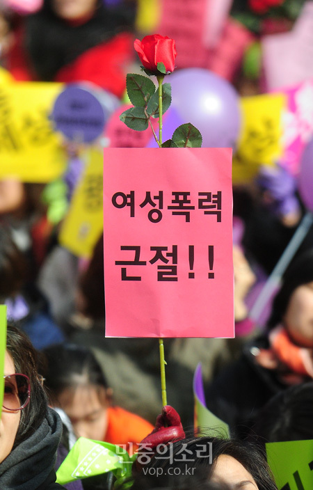 서울 청계광장에서 열린 3.8 세계여성의 날 기념 한국여성대회에서 한 참가자가 장미를 들고 폭력 근절을 요구하고 있다.