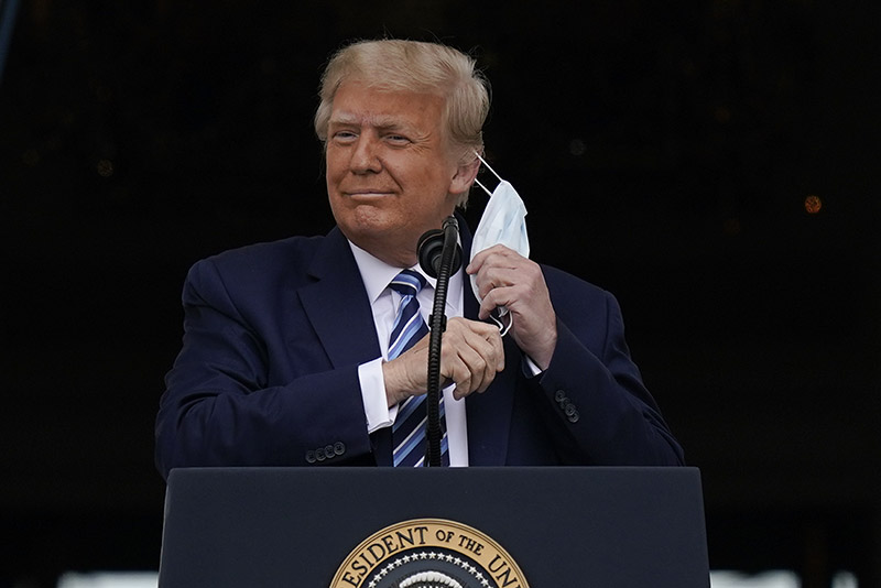 도널드 트럼프 미국 대통령이 10일 백악관 발코니에서 지지자들을 향해 연설을 하기 위해 마스크를 벗고 있다. (2020.10.10)