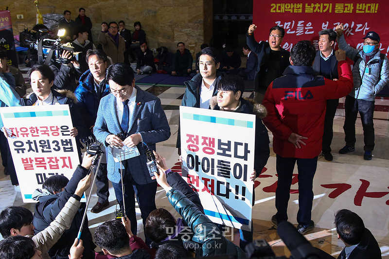 한국당 당원들(오른쪽)이 16일 국회 로텐더홀에서 유치원 3법 관련 기자회견을 하고 있는 박용진 더불어민주당 의원 뒤에서 구호를 외치며 방해하고 있다. 2019.12.16