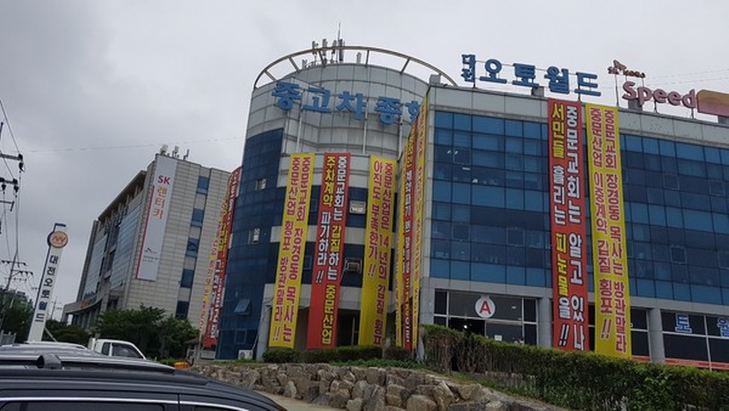 대전 오토월드 건물에 ‘중문교회는 알고 있나, 서민들 흘리는 피눈물을’, ‘중문산업 이중계약 갑질 횡포 중문교회 장경동 목사는 방관 말라’ 등의 문구가 담긴 현수막이 걸려 있다.