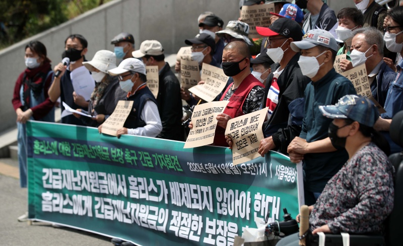 정부의 코로나19 긴급재난지원금 신청이 시작된 11일 빈곤사회연대, 홈리스행동 등 노숙인 관련 단체가 서울역 광장에서 기자회견을 열고 홈리스에 대한 긴급재난지원금 보장을 촉구하고 있다. 이날 기자회견에서 주최 단체는 빈곤에 따른 열악한 조건 속에서 홈리스들의 인터넷 신청이 어렵고 현장 신청 역시 주소와 거소의 분리, 거주불명등록 등의 이유로 어려운 것이 사실이고 카드와 상품권, 선불카드와 같은 지불수단은 홈리스의 필요를 채우는 데 큰 제약이 있다고 말하며 적절한